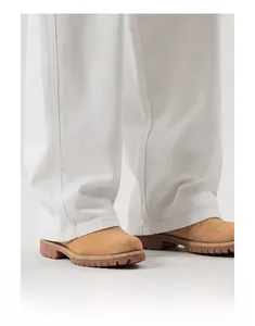 Détail d'un jean blanc à jambe large avec ourlet net et bottines de travail robustes