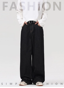 Detail of loose fit dark denim pants featuring a vintage belt and streetwear style