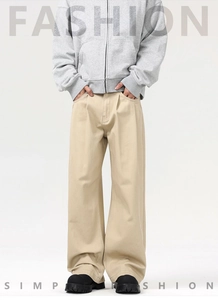 Detailed view of beige wide-leg trousers featuring a pleated waist and draped silhouette