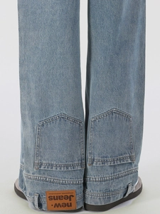 Back view of light blue denim jeans with brown leather waist patch and pocket detail
