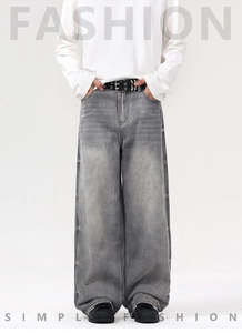 Détail d'un jean large gris délavé vintage avec ceinture noire à double trou et ourlet
