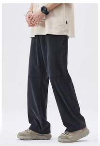 Detail of loose-fit straight trousers featuring knee panels and a washed fabric texture