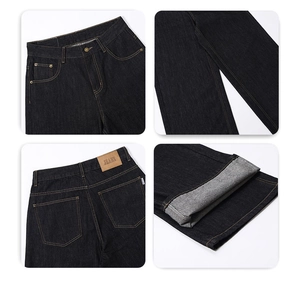 Detailed close-up of dark denim jeans featuring orange stitching and leather brand patch