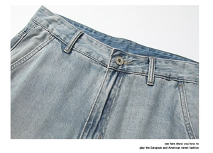 Détail du jean denim bleu clair montrant le bouton métallique et les passants de ceinture