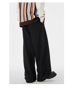 Side view of black wide-leg trousers with elegant drape on a model with boots