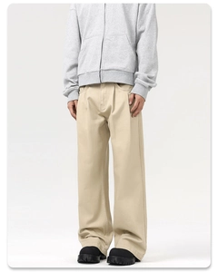Detail view of khaki pleated wide-leg trousers showing straight-cut fit and fabric texture