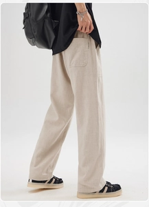 Detail view of cotton linen trousers showing pocket design and drape on male model