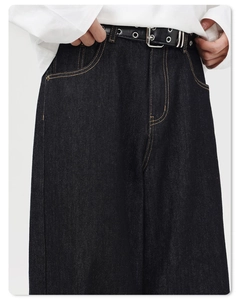 Detail of high-waist dark denim jeans with eyelet belt and orange contrast stitching