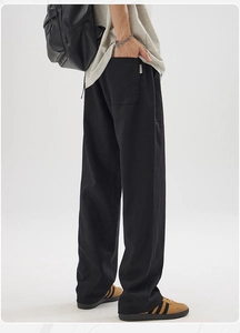 Detail view of men's black wide-leg linen trousers with back pocket and minimalist cut