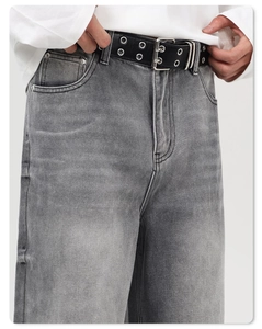 Détail d'un jean droit gris délavé avec ceinture à double œillets et style vintage