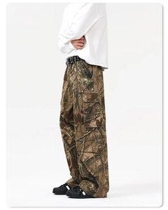 Detail view of cargo pants featuring tree branch camouflage print and large flap pockets