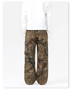 Macro detail of baggy cargo pants featuring realistic tree branch camouflage and side pockets