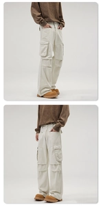 Detail view of multi-pocket cargo pants showing cream white fabric and straight leg cut