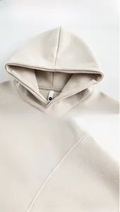 Detail view of the premium stitching and neck label on a heavy beige hooded sweatshirt