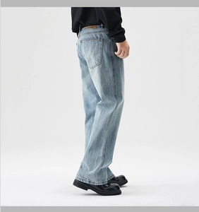 Detail view of light blue washed denim pants with brown leather waist tag and back pocket