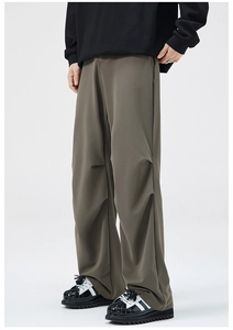 Detail of olive green wide-leg trousers featuring parachute pleats and a draped silhouette