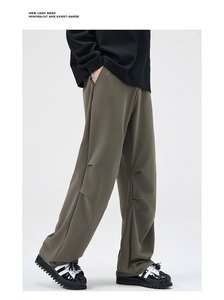 Detail of olive green wide-leg trousers featuring unique segmented pleated design on legs