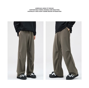 Detail showing the loose-fit pleated knees and draped fabric of these men's casual trousers