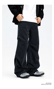 Detail of loose avant-garde black denim jeans featuring unique knee pleats and wide leg cut