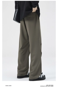 Detail view of olive green wide-leg trousers with drape fabric and rear flap pocket