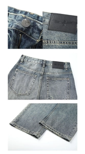 Dettaglio ravvicinato di bottone in metallo, patch in pelle e tasche usurate sui jeans