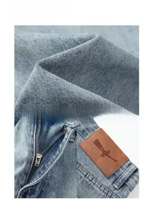 Detail of light blue vintage flared jeans featuring silver zipper and brown leather patch