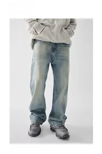 Detail of light blue washed denim jeans featuring a vintage distressed texture and loose fit