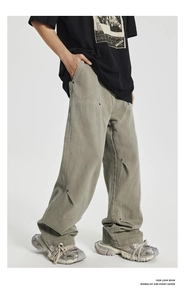 Detail of olive green carpenter pants with metal rivets and asymmetrical panels