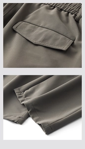 Detail of brown pleated trousers showing elastic waist, back flap pocket and hem stitching