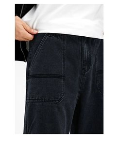 Close-up of black cargo denim jeans featuring large patch pockets and contrast stitching