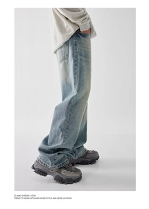 Detail of light blue vintage washed wide-leg jeans with natural distressed whiskering effect