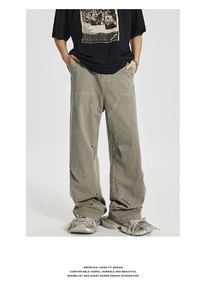 Detail showing structural patchwork and metal rivets on olive green carpenter pants