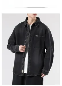 Detail of black denim jacket showing metal buttons and chest pocket with woven label