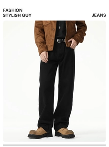 Detail of black straight-leg denim jeans styled with a vintage belt and brown boots