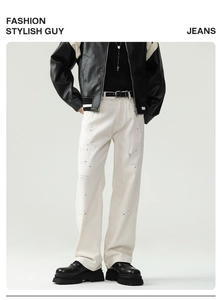Detail of off-white straight-cut jeans with distressed holes and black paint splatters