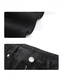 Detail of black denim fabric texture and silver metal button with engraved lettering