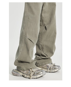 Detail view of washed olive carpenter pants with patchwork stitching and rivet accents