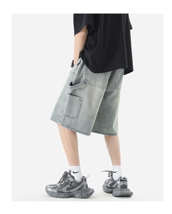 Detail showing vintage washed blue denim texture and cargo pocket stitching of the shorts