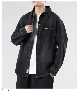 Detail of oversized black denim jacket featuring a chest pocket and minimalist logo tag