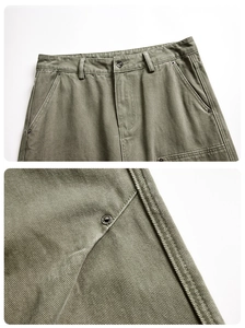 Detail view of olive cargo pants showing heavy twill fabric and reinforced metal rivets