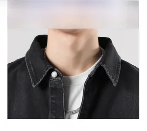 Close-up detail of a black denim jacket collar with silver button and white t-shirt layer