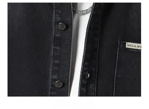 Detailed macro view of black twill denim jacket with branded tag and metallic buttons