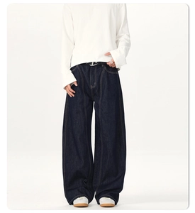 Detail of dark blue wide-leg jeans with contrast yellow stitching and metal logo belt