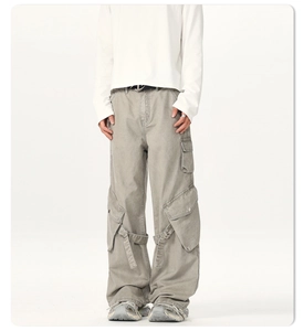 Close-up of light gray cargo pants with multi-pockets and unique buckle strap details