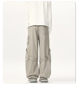 Macro shot of oversized cargo pants with ribbon details and multiple pockets in light grey