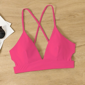 Close-up of rose pink bikini top with criss-cross back straps on wood background