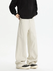 Detail view of cream wide-leg trousers showing heavy cotton fabric texture and drape