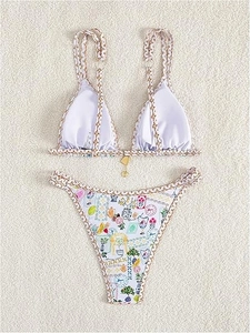Detail of floral print bikini with golden ring hardware on beige textured background