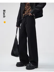 Detail of wide-leg black denim trousers with a draped fit and clean silhouette design