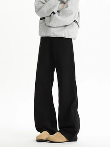 Close-up of black wide-leg trousers paired with grey hoodie and suede mules on white background